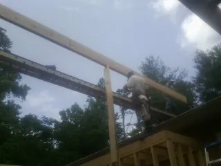 Carpenter setting a ridge beam over a new addition frame — Ice Dam Removal by Roofing Brothers in Calvin