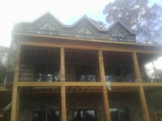 Dormers and porch framing on a large log home under construction — Roof Coating work by our crew in Calvin