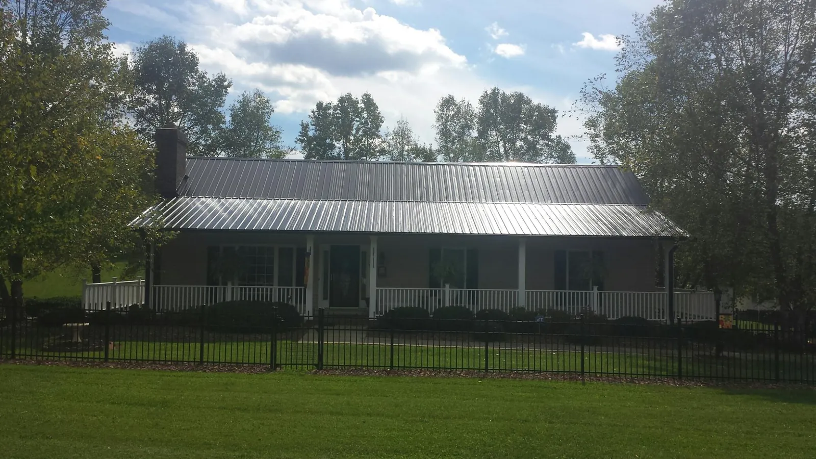 Gray metal roof on a brick ranch with a full width front porch — Gutter Guard Installation work by our crew in Calvin