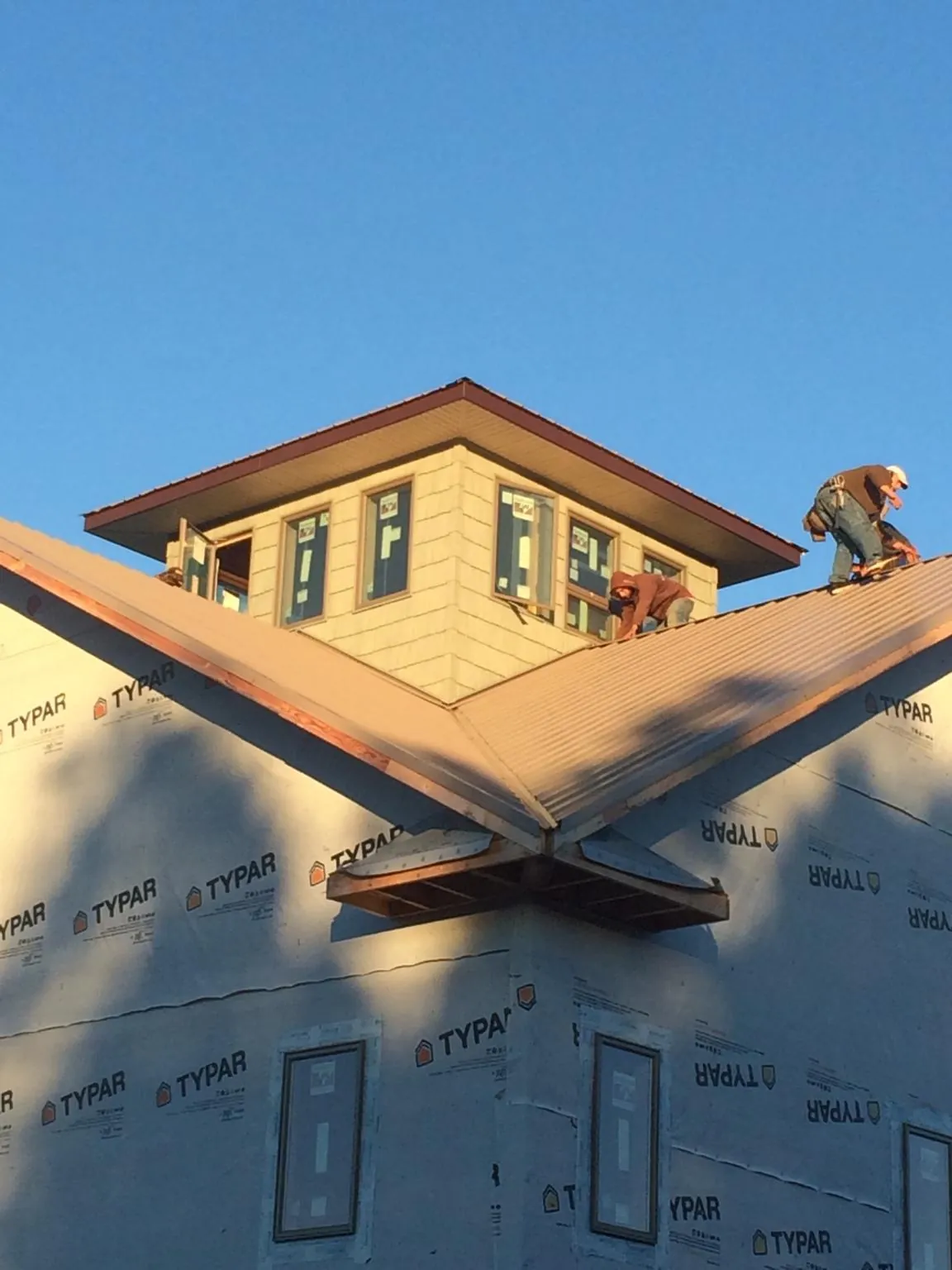 Roofers working around a rooftop cupola on a new metal roof at sunset — Roof Waterproofing in Calvin by Roofing Brothers